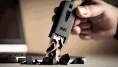 O imagine a unei persoane care ține în mână o unitate flash USB cu un distrugător în fundal